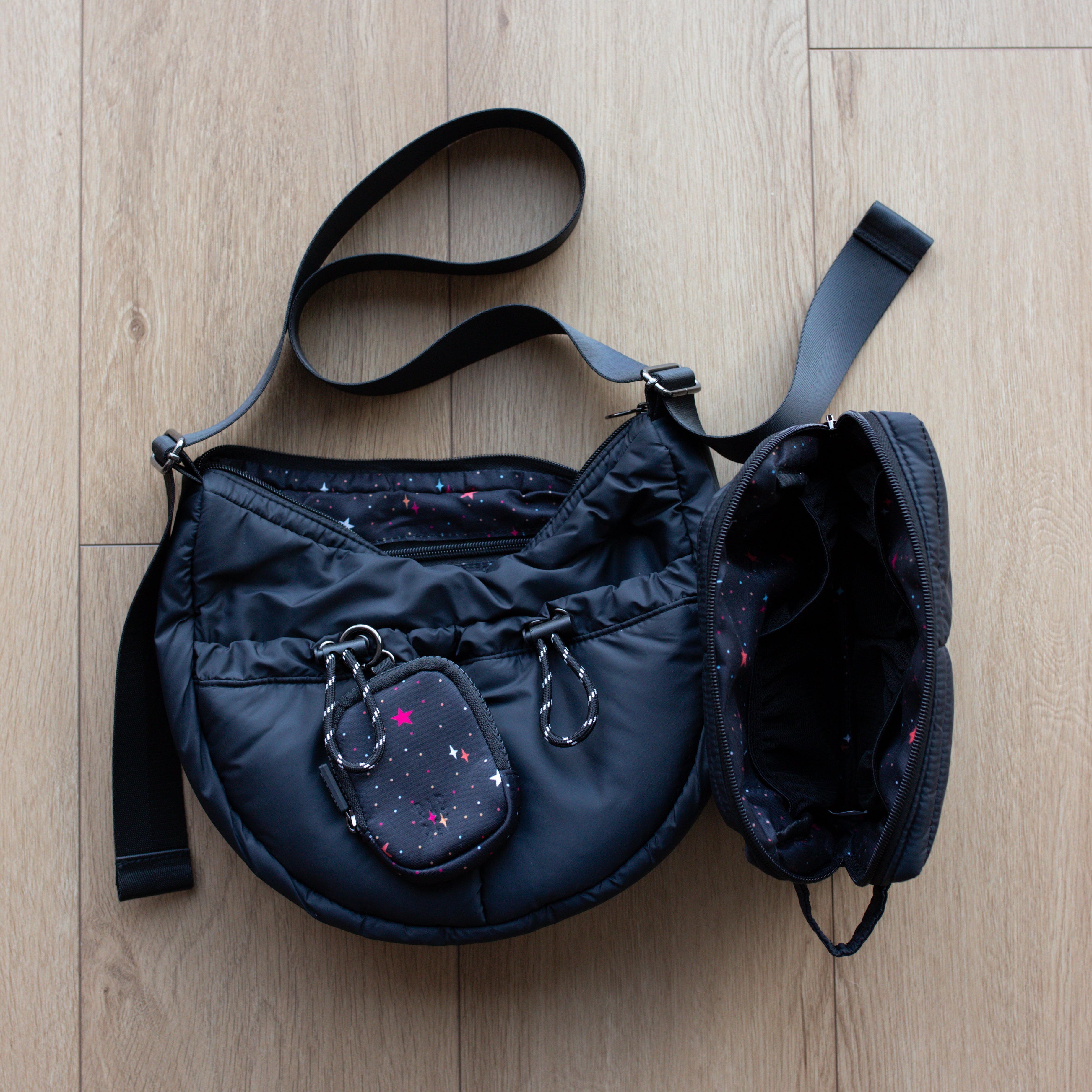 Black handbag with a strap on a wooden floor