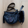 Black handbag with a strap on a wooden floor
